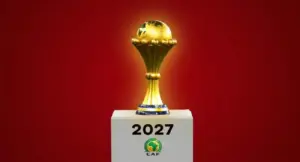 كأس إفريقيا الذهبية موضوعة على منصة تحمل شعار الكاف وعام 2027، تُستخدم كصورة تعبيرية لمقال حول مشاركة 48 منتخباً في تصفيات الكان.