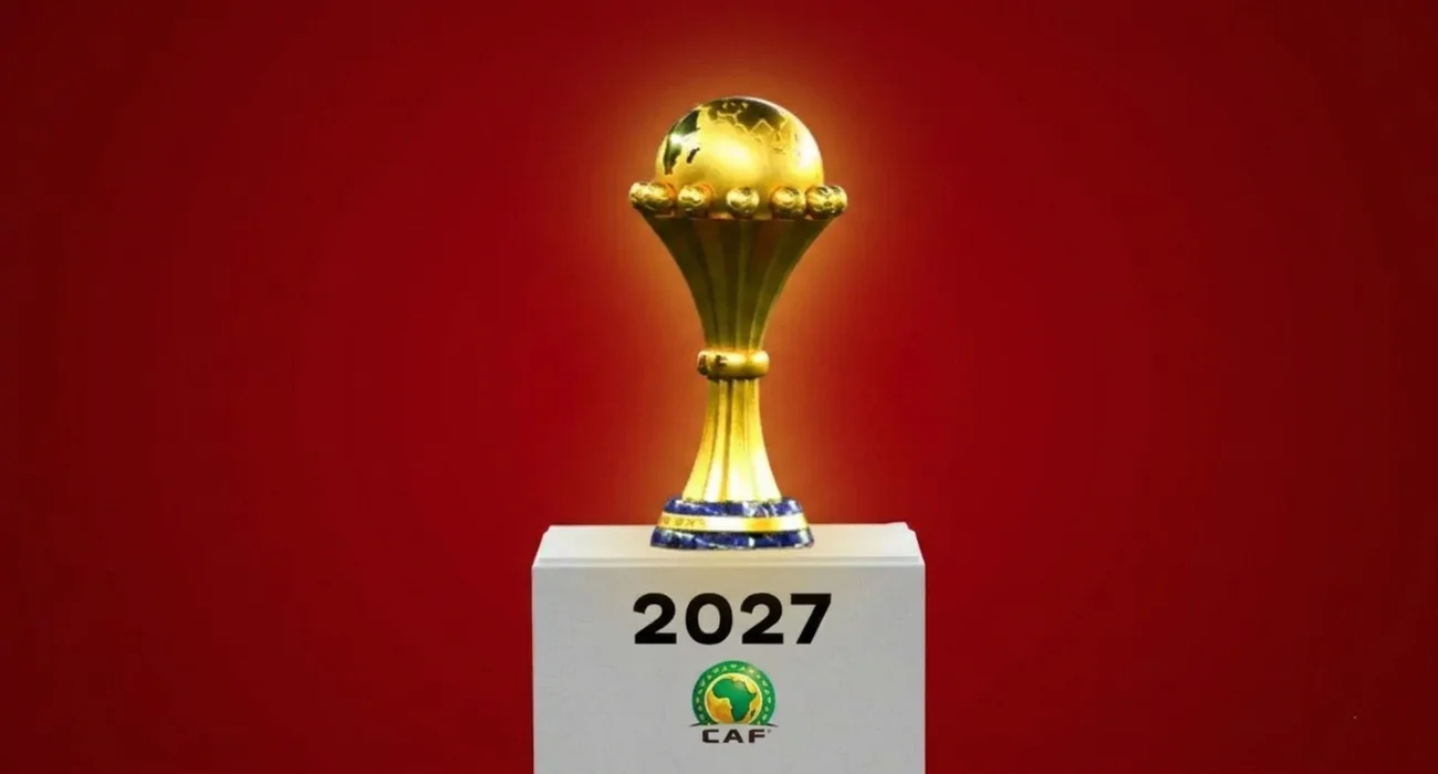 كأس إفريقيا الذهبية موضوعة على منصة تحمل شعار الكاف وعام 2027، تُستخدم كصورة تعبيرية لمقال حول مشاركة 48 منتخباً في تصفيات الكان.