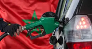 مضخة وقود تزود سيارة بالبنزين أمام العلم المغربي، تُستخدم لتوضيح تقرير حول توضيحات المرصد المغربي لحماية المستهلك بشأن اختلالات أسعار المحروقات في المغرب.